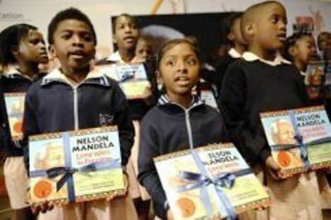 Un groupe d’écoliers tiennent un exemplaire du livre de Nelson Mandela Long walk to Freedom dans une version pour enfants, le 17 juillet 2011 à Johannesbourg