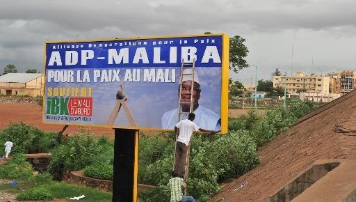 Un homme colle une affiche de campagne le 8 août 2013 à Bamako